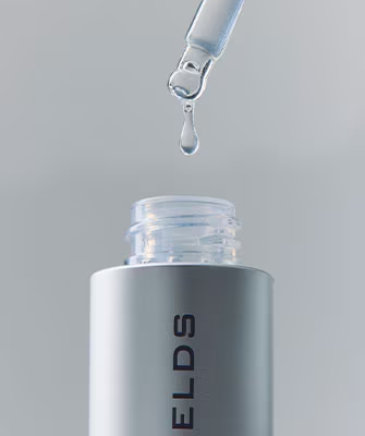 Dropper dispensing clear serum above a Rodan + Fields bottle